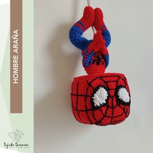 May include: A crocheted Spiderman hanging upside down from a string. The figure is red and blue with a black spider design on the chest. The figure's eyes are white and the web design is black.