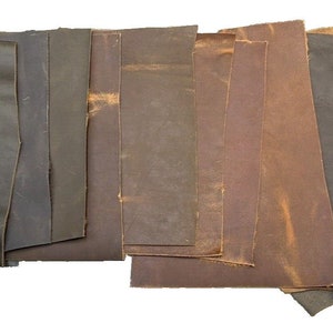 May include: Assortment of leather scraps in various shades of brown, gray, and tan. The leather pieces are arranged in a row, with the darkest shade on the left and the lightest shade on the right.