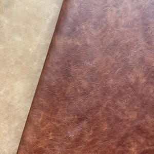 May include: Two pieces of leather fabric, one beige and one brown, are shown side by side. The brown leather has a distressed look with a textured surface.