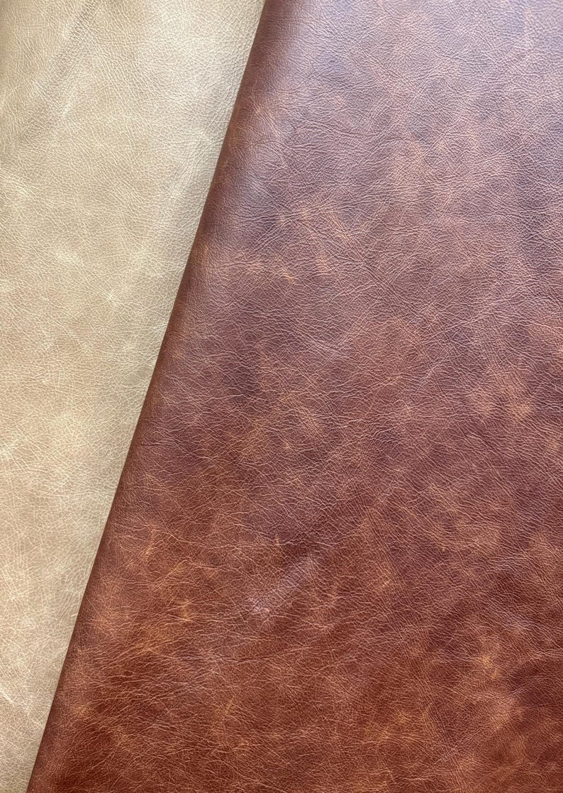 May include: Two pieces of leather fabric, one beige and one brown, are shown side by side. The brown leather has a distressed look with a textured surface.