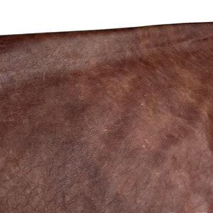 May include: Close-up of a brown leather surface with a textured, worn look.