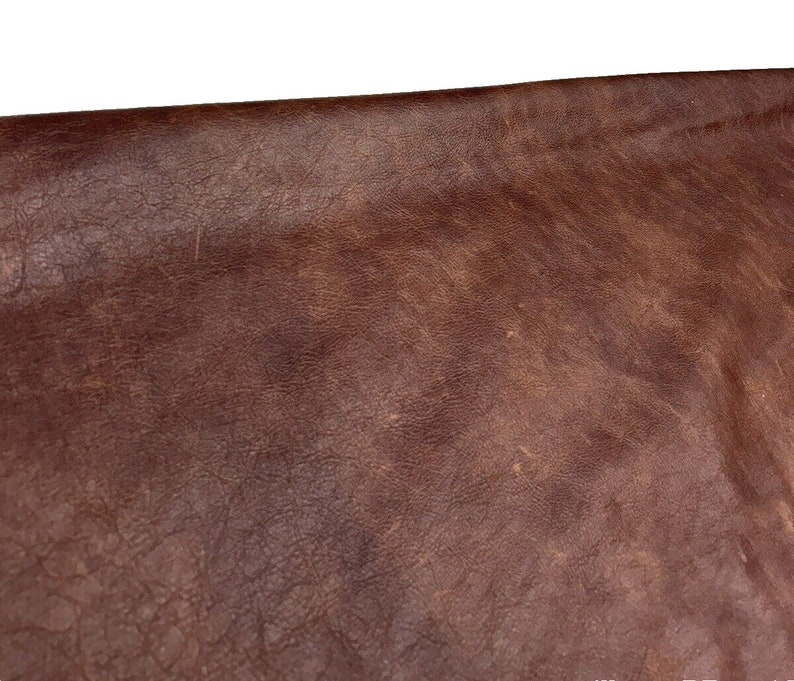 May include: Close-up of a brown leather surface with a textured, worn look.