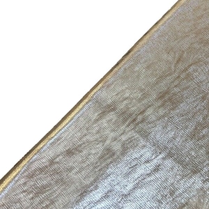 May include: Close-up of a metallic gold fabric with a subtle shimmer. The fabric has a woven texture and a smooth, silky feel.