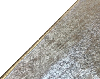 May include: Close-up of a metallic gold fabric with a subtle shimmer. The fabric has a woven texture and a smooth, silky feel.