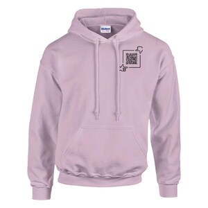 Op de afbeelding: Een lichtpaarse hoodie met een voorzak en een capuchon met trekkoord. De hoodie heeft een zwarte afbeelding van een QR-code met een wijzende vinger en een duim omlaag symbool. De merknaam "Gildan" is zichtbaar op de capuchon.