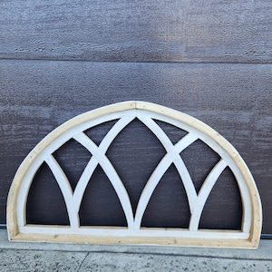 Puede incluir: Un arco de madera blanco con un diseño decorativo de ventana de vitral geométrico. El arco está hecho de madera y tiene un acabado de madera natural.