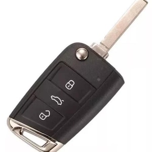 Op de afbeelding: Een zwarte autosleutel met een zilveren sleutelblad en sierlijst. De sleutel heeft drie knoppen met witte pictogrammen voor vergrendelen, ontgrendelen en het openen van de kofferbak. De sleutel is rechthoekig met afgeronde hoeken.