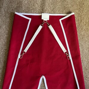 May include: Red fabric garment with white trim and straps, featuring metal hardware. The garment has a split at the bottom and the text "Custom order example: (21st Nova Corps)" at the top.