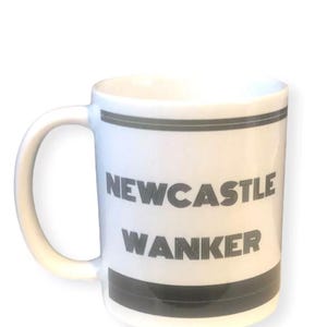 May include: White ceramic mug with a curved handle. The mug features the text "NEWCASTLE WANKER" in gray block letters, with gray bands at the top and bottom. The mug is set against a white background.