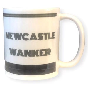 May include: White ceramic mug with a black handle and rim. The mug features the words "NEWCASTLE WANKER" in bold, black capital letters. The mug has a simple, clean design.