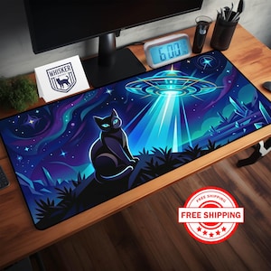 May include: A black mousepad with a vibrant illustration of a black cat with glowing blue eyes, gazing at a UFO beaming a light. The background features a starry night sky with purple and blue hues. The mousepad has the "Whisker Wonders" logo.