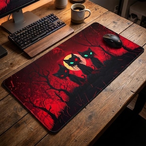 May include: A rectangular mouse pad featuring a spooky Halloween design. The pad has a red background with a full moon and silhouettes of black cats with glowing eyes. The design includes bare trees, creating a haunted atmosphere.