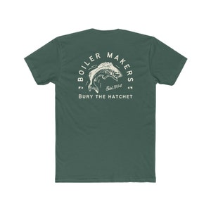 May include: A dark green t-shirt with a white graphic of a fish jumping out of the water. The graphic is surrounded by a circle with the text "Boiler Makers Est. 1994" and the words "Bury the Hatchet" below.