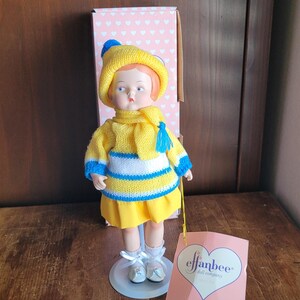 Puede incluir: Una muñeca vintage Effanbee Patsyette Winter. La muñeca lleva un gorro de punto amarillo con un pompón azul, una bufanda a juego y un suéter amarillo con rayas azules y blancas. La falda de la muñeca es amarilla y lleva zapatos blancos.