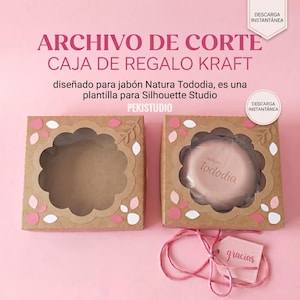 May include: Kraft gift box with a floral cutout design, holding a round soap. The box is brown with pink and white accents. Text on the box reads "ARCHIVO DE CORTE CAJA DE REGALO KRAFT" and "PEKISTUDIO". A tag with the word "gracias" is attached.