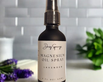 May include: A black bottle with a spray nozzle, labeled "Daisy Springs Magnesium Oil Spray Lavender 2 fl oz / 60 ml".