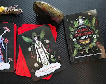 May include: A set of tarot cards with black backgrounds and colorful illustrations. The cards are titled "Fly Agaric" and "Lily of the Valley". The cards are part of a deck called "Deadly Apothecary Oracle: Poisonous Plants as Guides and Healers".