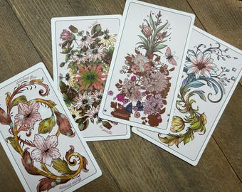 May include: Four rectangular oracle cards with white borders featuring detailed botanical illustrations. The cards display floral arrangements and swirling vine motifs in muted tones of pink, green, and brown, with text including 'abundant flow', 'be bold', 'be gentle', 'control', 'surrender', 'dormant energy', and 'expansion'.