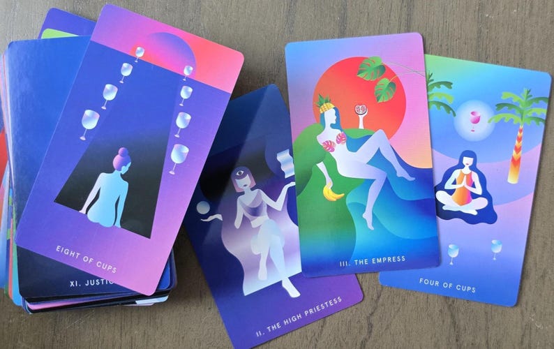 May include: A deck of tarot cards with colorful illustrations. The cards feature images of figures, cups, and palm trees. The Eight of Cups, The Empress, The High Priestess, and Four of Cups are visible. The cards have a gradient color scheme of purple, blue, and pink.