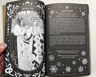 May include: An open book with black pages and white ink illustrations. The left page features a detailed drawing of two figures labeled Morana, surrounded by flames and snakes. The right page contains text about January, snowflakes, and goddess attributes.