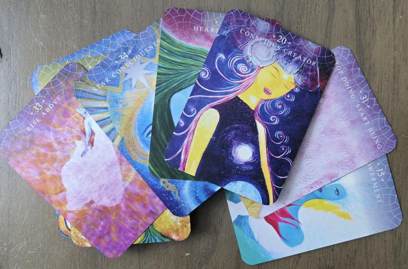 May include: A set of colorful oracle cards with various images and text. The cards feature a variety of themes, including "Star Consciousness", "Heart", "Conscious Creator", "Rise Above", "Top Doing, Start Being", and "Investment".
