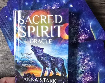Peut inclure: Un jeu de cartes d'oracle avec un fond bleu, violet et or. La boîte présente un loup hurlant à la lune avec le texte "SACRED SPIRIT ORACLE" et "Spiritual guidance for your life journey" et "ANNA STARK".