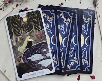 May include: A tarot card with a forest scene and the text "Ascending to Spring" is displayed with several other cards. The card's back has a navy blue background with crescent moons, stars, and botanical illustrations. The main card features a figure with long green hair.