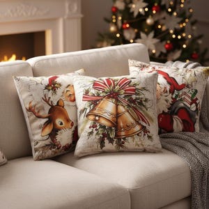 Peut inclure: Quatre coussins décoratifs de Noël avec des motifs festifs. Un coussin présente un renne, un autre le Père Noël, et un troisième met en valeur des cloches dorées avec un nœud rouge. Les coussins sont sur un canapé beige.