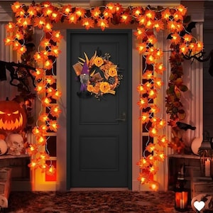 Può includere: Una porta d'ingresso a tema Halloween decorata con luci a corda a forma di foglie arancioni, una ghirlanda di fiori e uno gnomo. Una zucca intagliata e teschi sono sul portico.