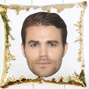 May include: A gold and white reversible sequin pillow with a man's face printed on the white side.