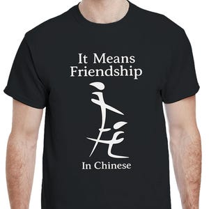 Könnte beinhalten: Schwarzes T-Shirt mit dem weißen Text "It Means Friendship" und chinesischen Schriftzeichen. Das T-Shirt hat einen Rundhalsausschnitt.