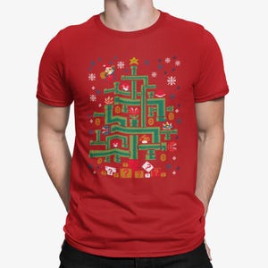 May include: Red t-shirt featuring a green Christmas tree design made of video game elements. The design includes characters, coins, and question mark blocks. Snowflakes and a star complete the festive look.