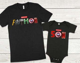 May include: Black t-shirts with a Marvel-themed design. The larger shirt says "Marvelous Father" with the letters replaced by Marvel character symbols. The smaller shirt says "Marvelous Son" with the letters replaced by Marvel character symbols.