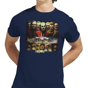 May include: Navy blue t-shirt featuring a graphic of multiple Joker characters reflected in water. The image includes various depictions of the Joker, with a focus on the character's iconic makeup and attire. The shirt is made of a soft material.