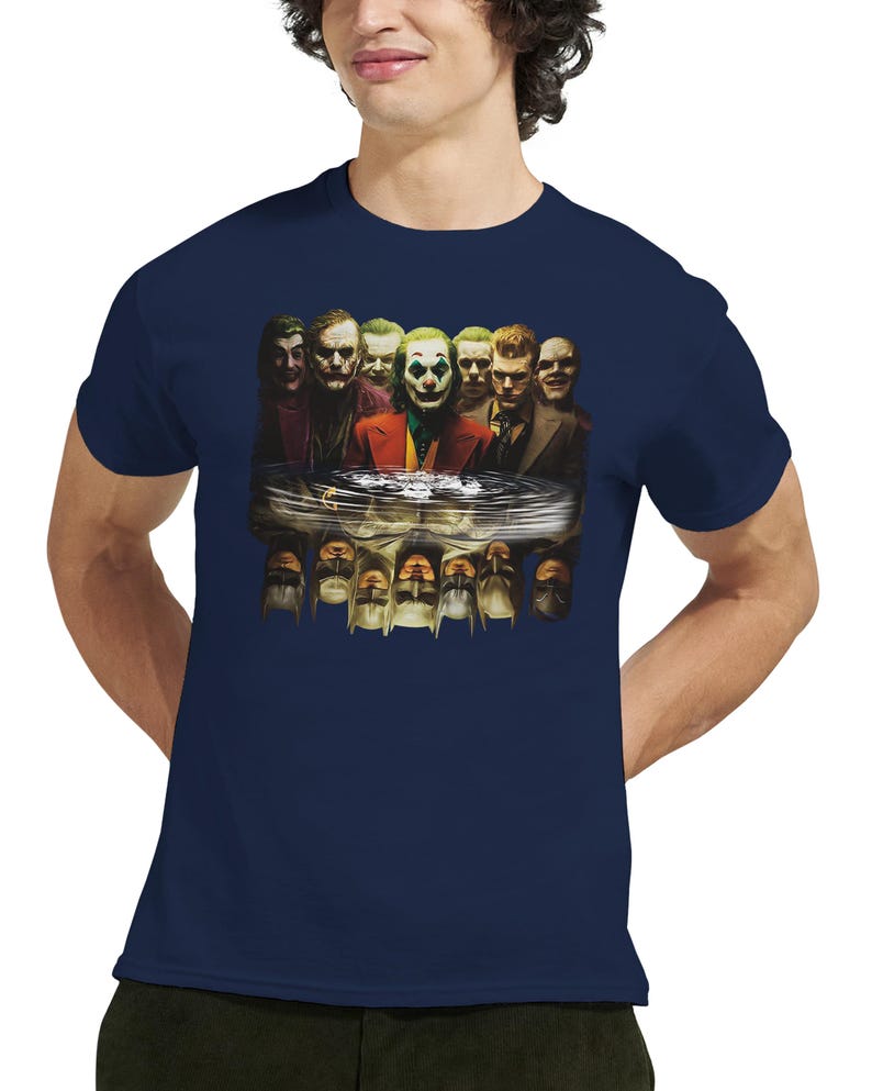 May include: Navy blue t-shirt featuring a graphic of multiple Joker characters reflected in water. The image includes various depictions of the Joker, with a focus on the character's iconic makeup and attire. The shirt is made of a soft material.
