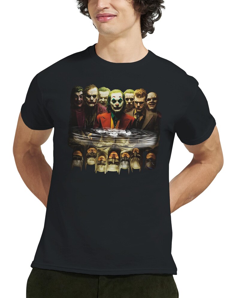 May include: Black t-shirt featuring a graphic of multiple Joker characters. The image includes various depictions of the Joker, with a central figure in a red suit and green hair. The design is a detailed illustration.