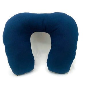 May include: A navy blue travel pillow with a U-shape design. The pillow is made of a soft fabric and is designed to support the neck and head. The pillow is a solid navy blue color.