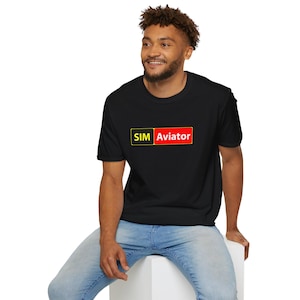 May include: Black t-shirt with the text "SIM Aviator" in a yellow and red rectangle. The shirt is a crew neck style and is being worn by a person.