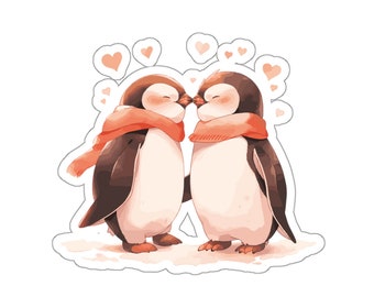 以下が含まれることがあります： 目を閉じて向き合う2羽のペンギンが描かれたステッカー。どちらもオレンジ色のスカーフを巻いています。ペンギンの上には、白い背景に浮かぶ小さな薄いオレンジ色のハートがいくつか描かれています。