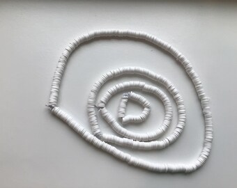 May include: A white string of round beads arranged in a spiral pattern.