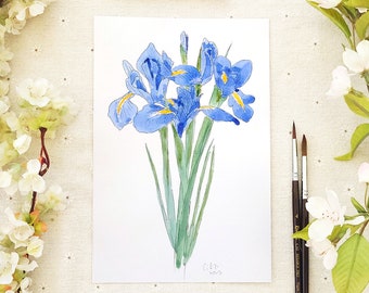 May include: Watercolour painting of a bouquet of blue irises with yellow centres. The flowers are painted in a realistic style with delicate details. The painting is signed "Gift 2023" in the bottom right corner.