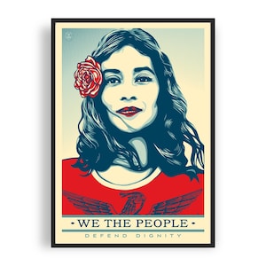 Peut inclure: Impression d'art encadrée représentant une femme avec des cheveux foncés et une rose rouge, vêtue d'un haut rouge avec un aigle. Le texte "WE THE PEOPLE - DEFEND DIGNITY" est en bas, dans un style graphique audacieux.