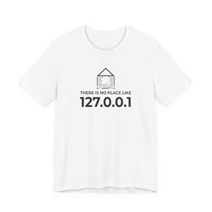 Peut inclure: Un t-shirt blanc à manches courtes avec un motif noir représentant le contour d'une maison intégré à des motifs de circuits imprimés. Sous le graphique, le texte indique : THERE IS NO PLACE LIKE 127.0.0.1 dans une police sans empattement.