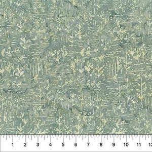May include: A close-up of a fabric with a repeating pattern of white leaf and stem designs on a blue-green background. A ruler is at the bottom, showing measurements in inches.