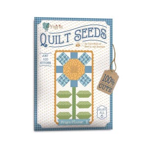 May include: A quilt pattern featuring a flower with blue and yellow fabric. The pattern is called "Prairie Flower 1" and is part of the "Quilt Seeds" collection by Lori Holt of Bee in my Bonnet. The text "100% Cute" is on a brown tag.