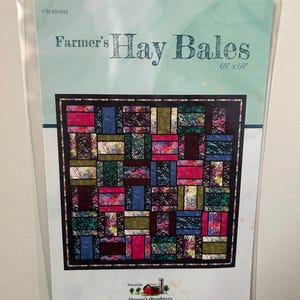 May include: A quilting pattern for a quilt called "Farmer's Hay Bales" by Farmer's Daughters Quilts. The pattern is for a quilt that is 69 inches by 69 inches. The quilt design features a patchwork of squares in various colors and patterns.