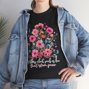 Könnte beinhalten: Schwarzes T-Shirt mit einem Blumendesign aus rosa, orangefarbenen und blauen Blumen, gebunden mit einem rosa Band. Der Text "Mothers plant seeds of love that bloom forever" ist in weißer Schrift gedruckt.
