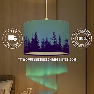 May include: A cylindrical pendant lamp with a teal and blue gradient shade. The shade features a dark purple silhouette of a forest. The text "TwoRiversExchange.Etsy.com" is visible at the bottom of the image.