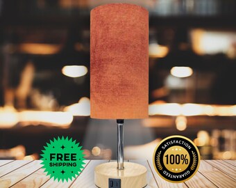 May include: A USB touch lamp with a cylindrical orange lampshade. The lamp has a silver stem and a wooden base with USB ports. The text "USB Touch Lamp" is at the top of the image.