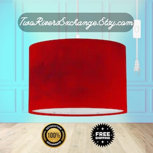 Peut inclure: Un abat-jour cylindrique rouge suspendu au plafond. L'abat-jour a un intérieur blanc et est suspendu par un cordon blanc. Le texte "Two Rivers Exchange.Etsy.com" est au-dessus de l'abat-jour.